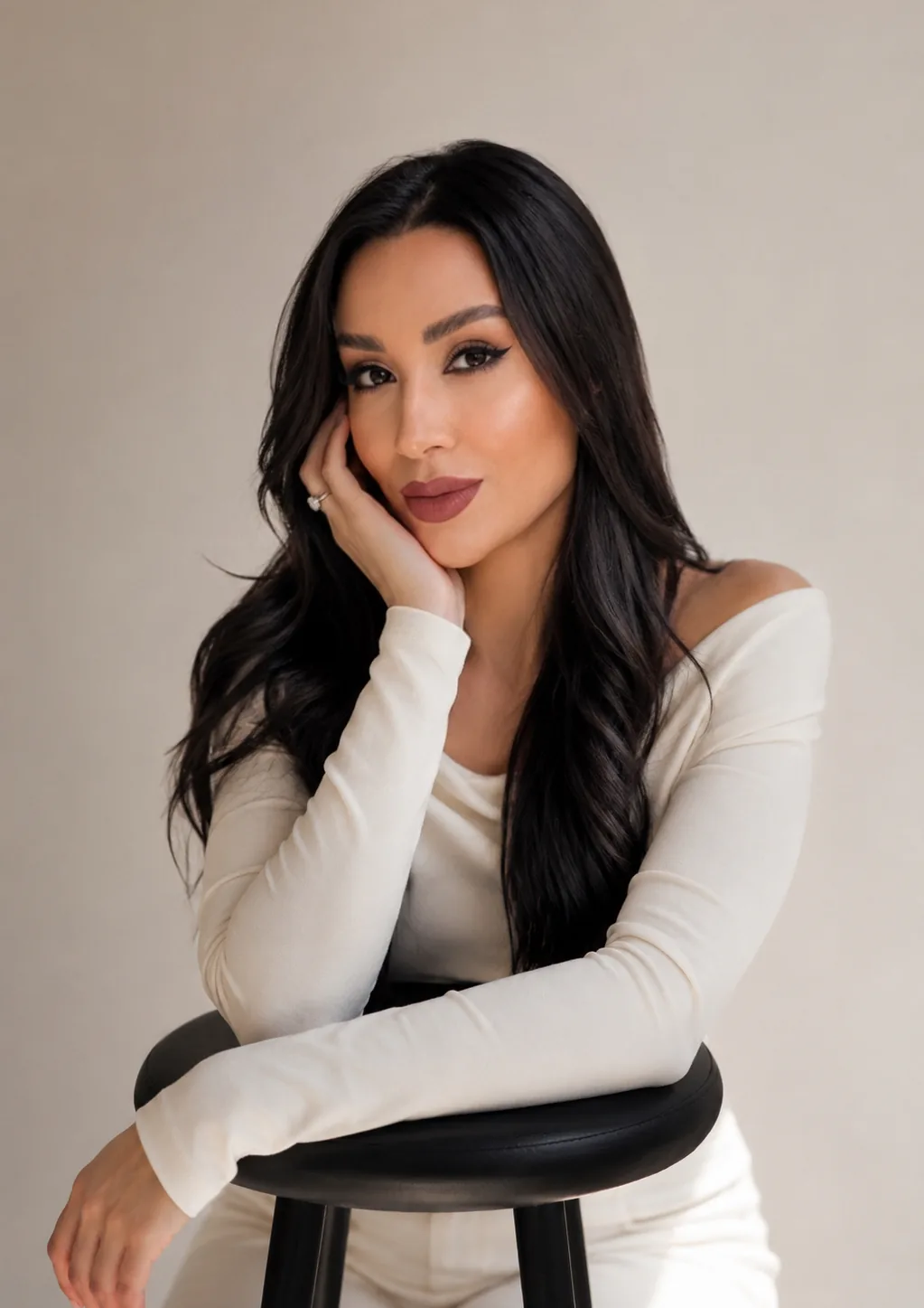 Jessica Mendes apoiada em um banco alto, retrato em fundo claro